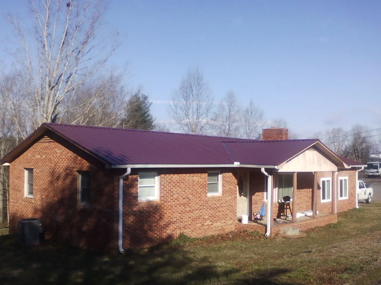 Burgundy metal roof on a brick ranch home with a new addition in Jessie