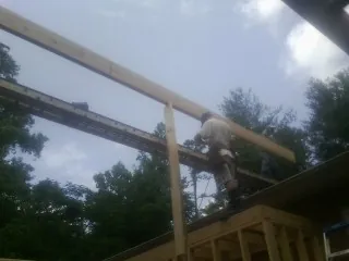Carpenter setting a ridge beam over a new addition frame — Ice Dam Removal by Roofing Brothers in Jessie