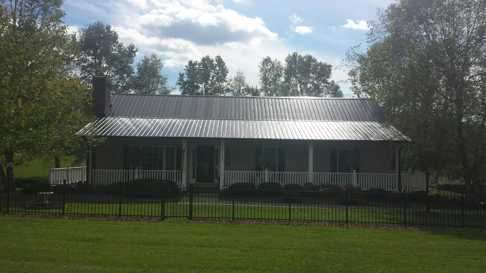 Gray metal roof on a brick ranch with a full width front porch — Gutter Guard Installation work by our crew in Jessie