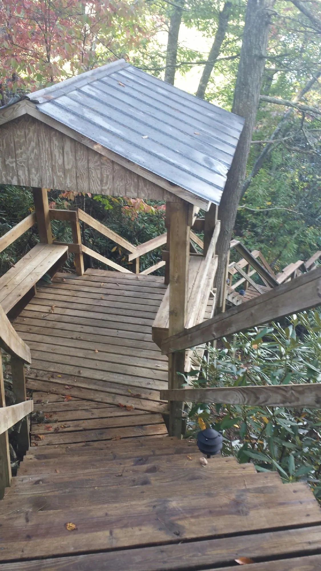 Metal roofed shelter over wooden steps on a wooded walkway — Skylight Repair & Installation work by our crew in Jessie
