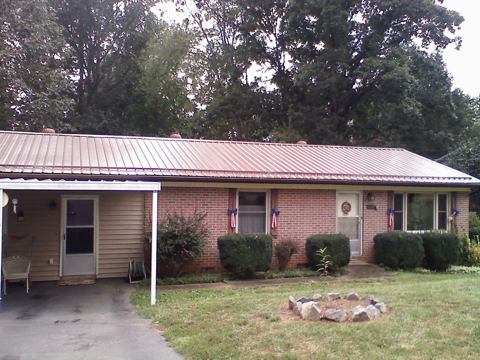 Bronze metal roof and carport on a brick ranch home — Roof Repair work by our crew in Jessie