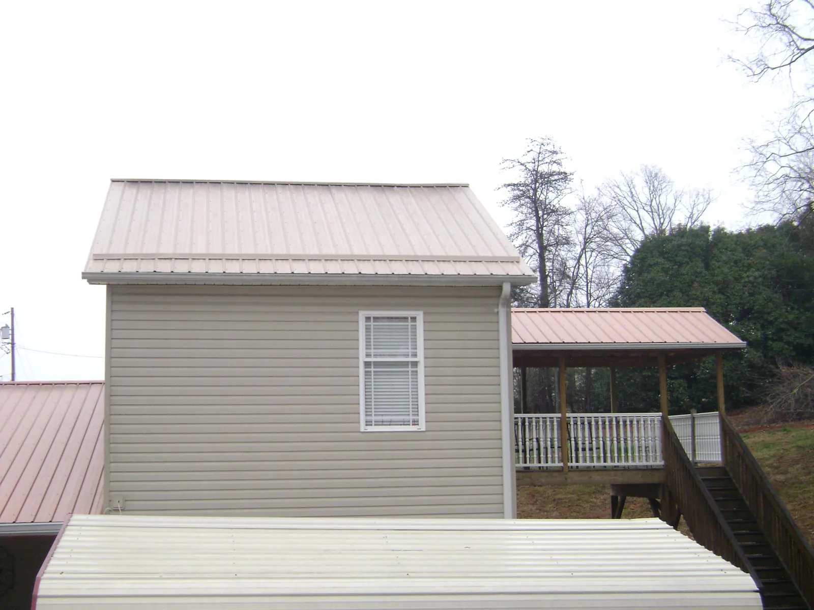 Tan metal roofs on a two story addition and attached porch, from a Roof Replacement job in Jessie